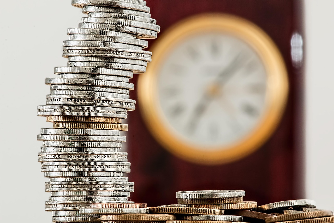 Stacks of coins next to a small model house and calculator, representing budgeting before investing.