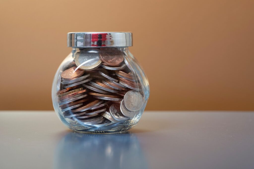 A glass jar filled with coins representing savings ready to be invested