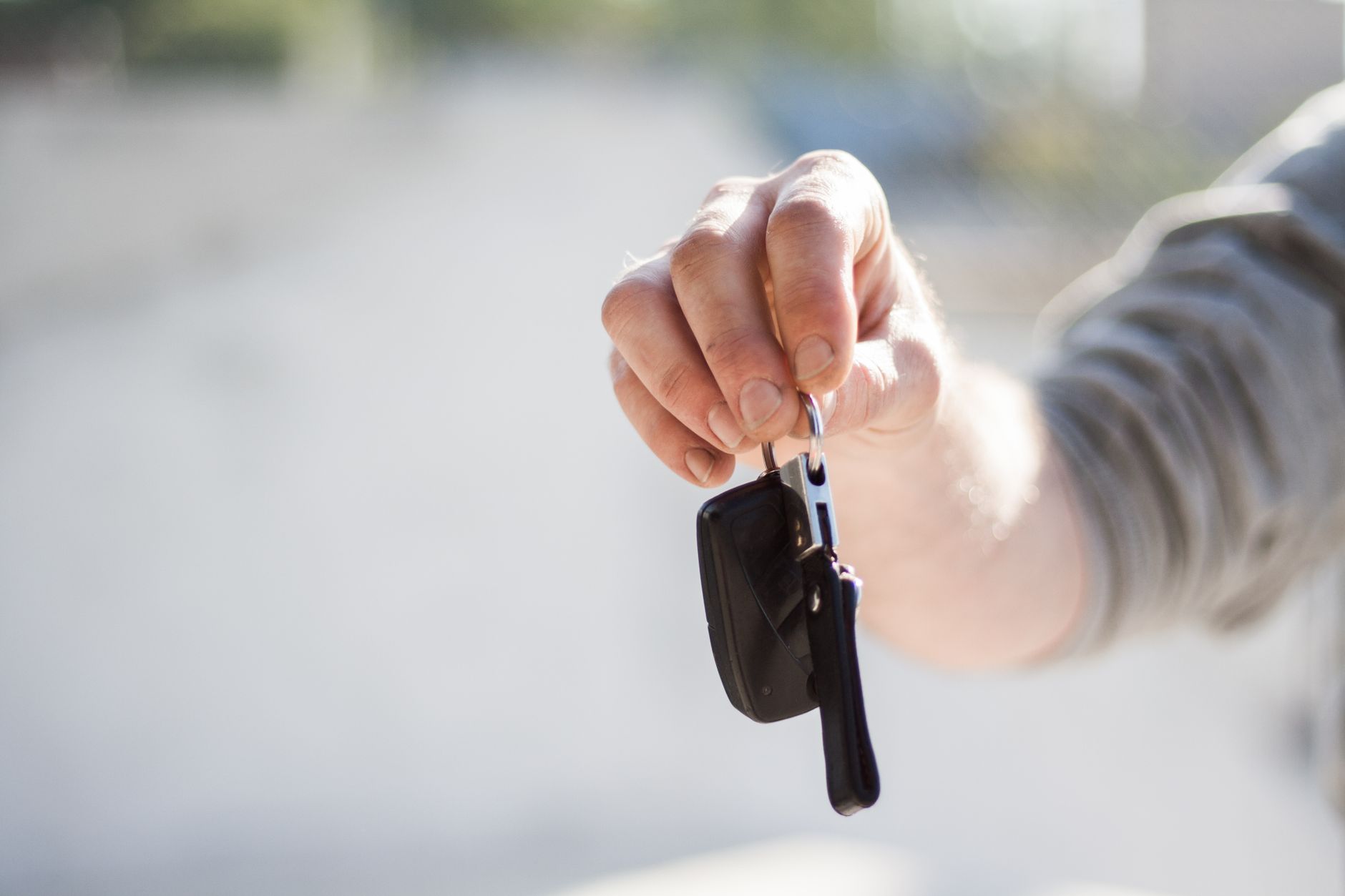 A close-up of a buyer receiving car keys from a dealer to symbolize the start of an auto loan.