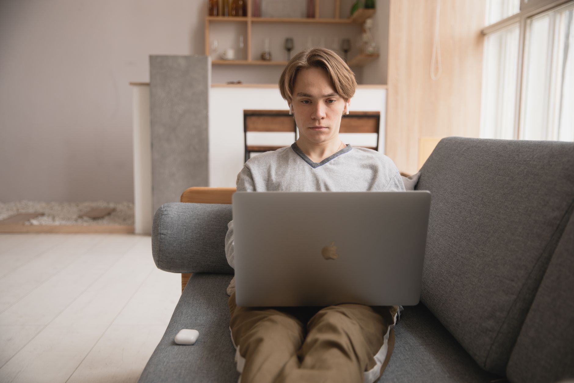 A young professional sitting comfortably on a couch with a laptop, smiling and drinking coffee, representing stress-free financial management