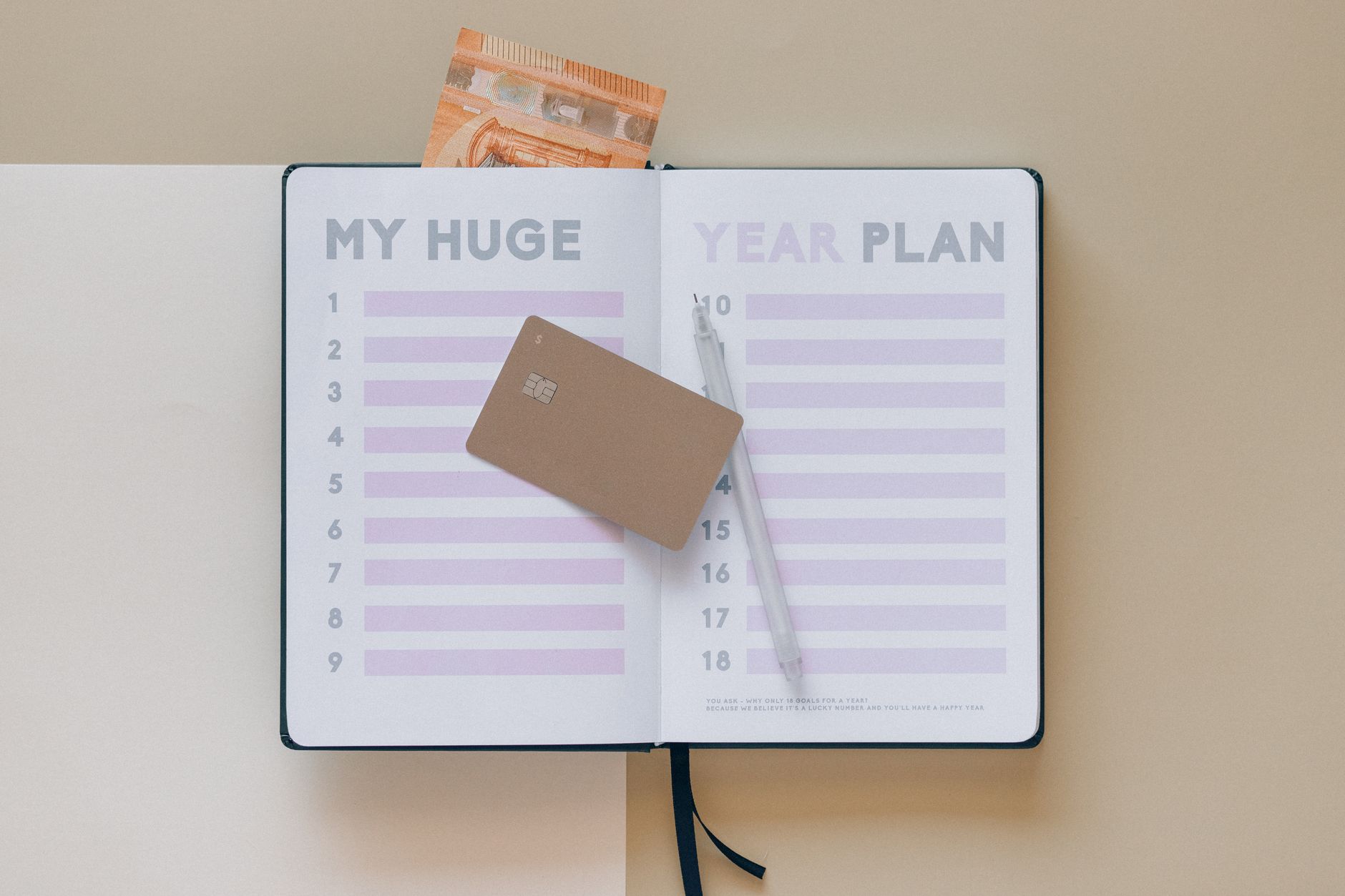 A hand marking a calendar with a payment due date for a credit card, symbolizing timely payments.