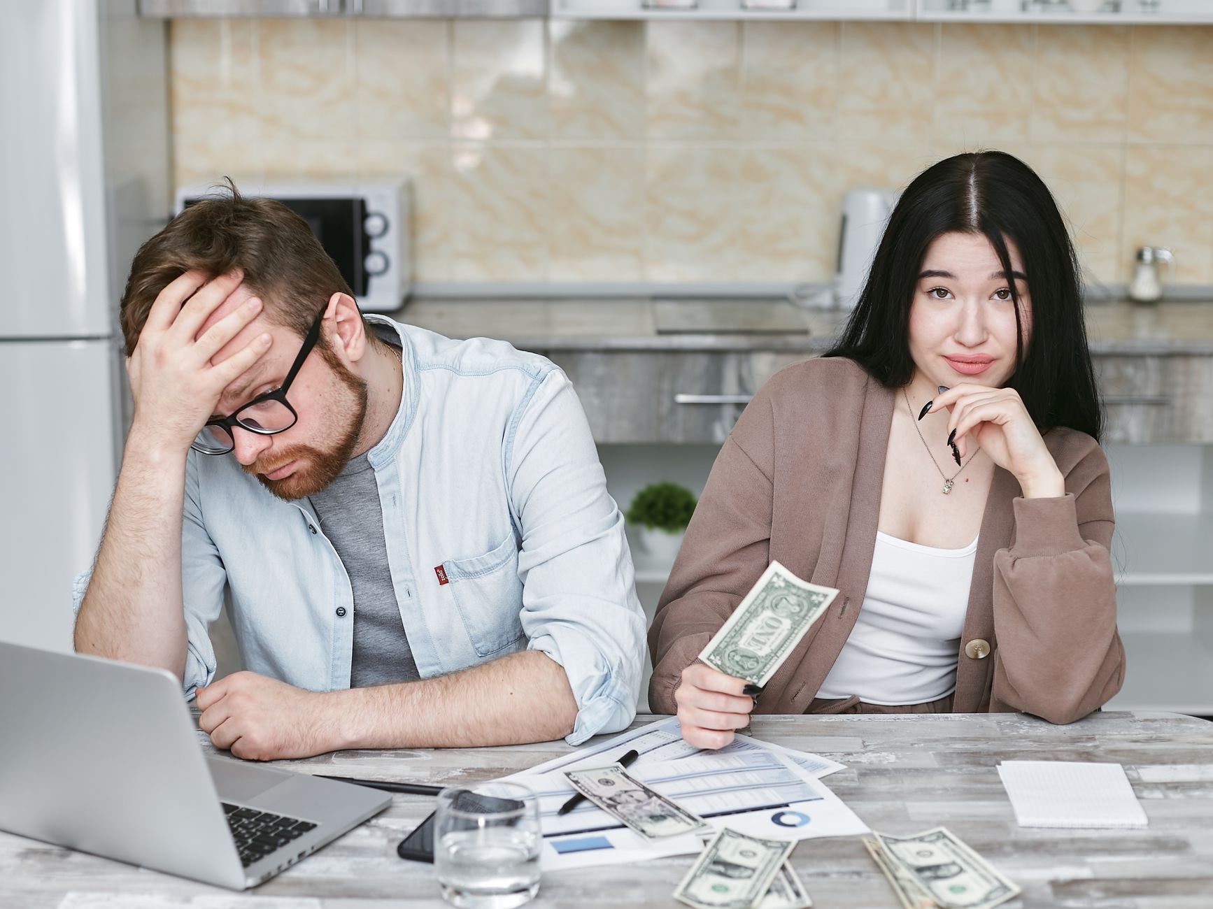 A young couple sitting on the living room floor discussing their savings goals and looking at a tablet