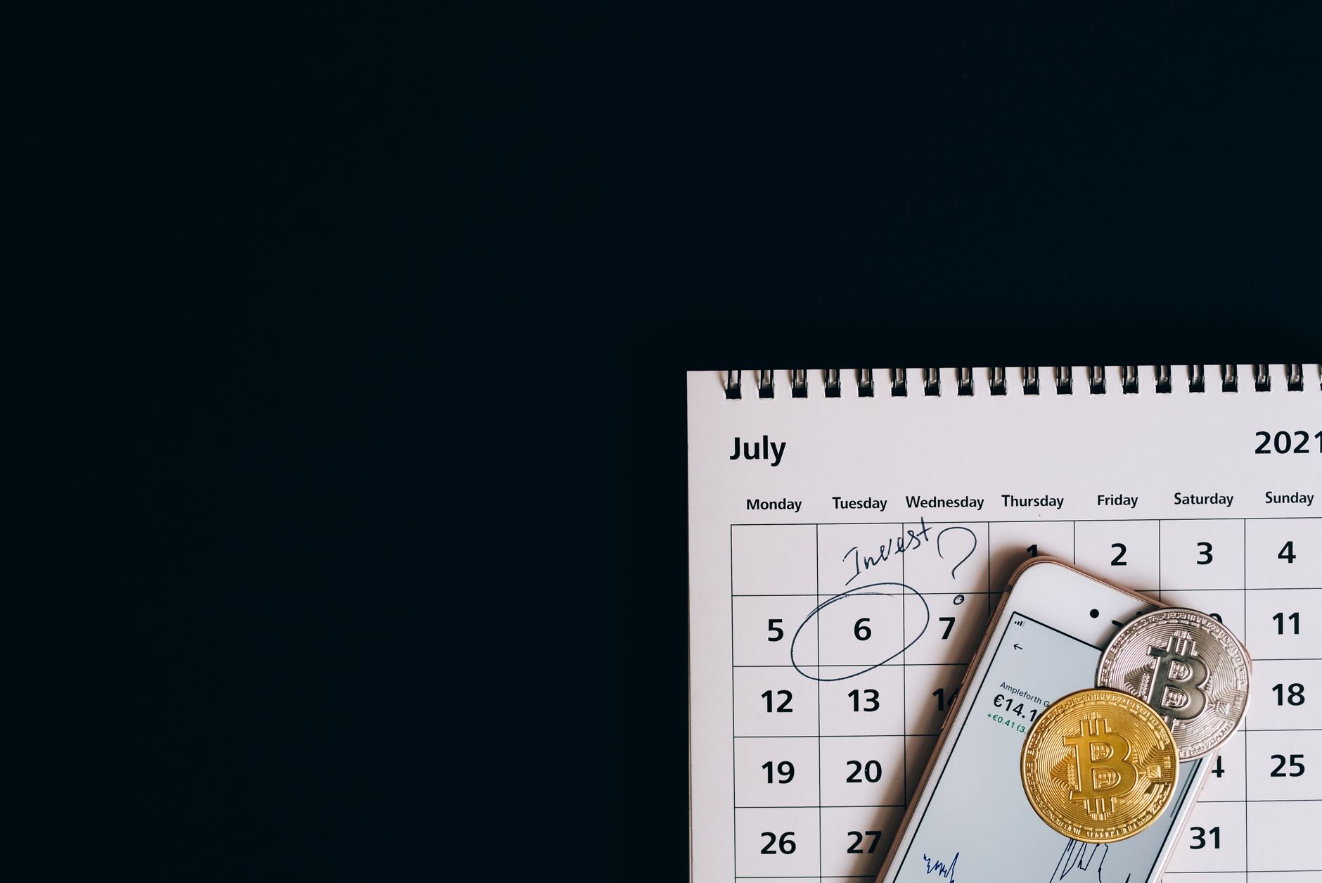 A calendar with a circular mark on the end of the month next to a smartphone displaying financial apps