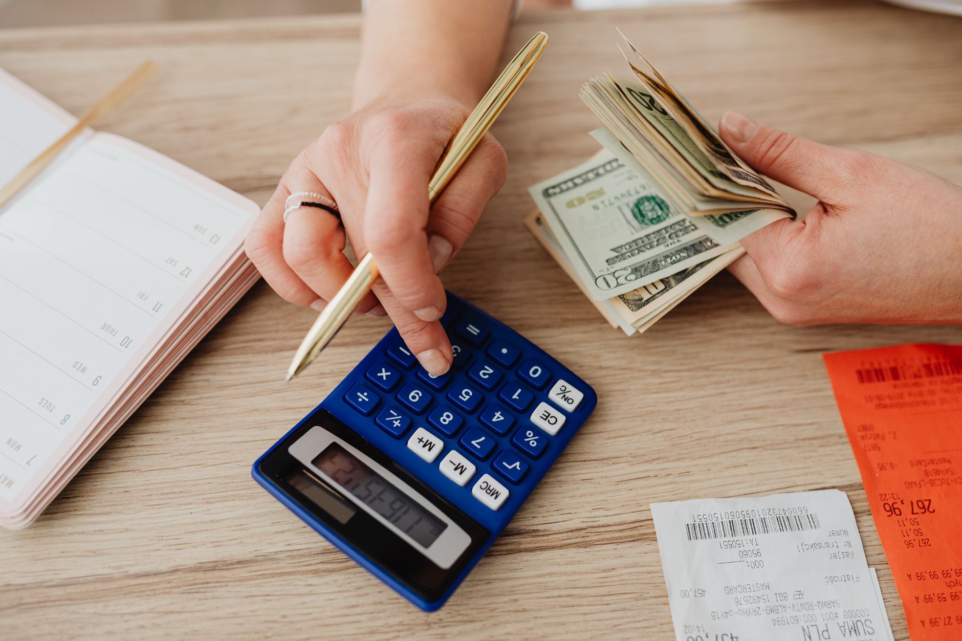 A person using a calculator and notepad to draft a zero-based budget layout
