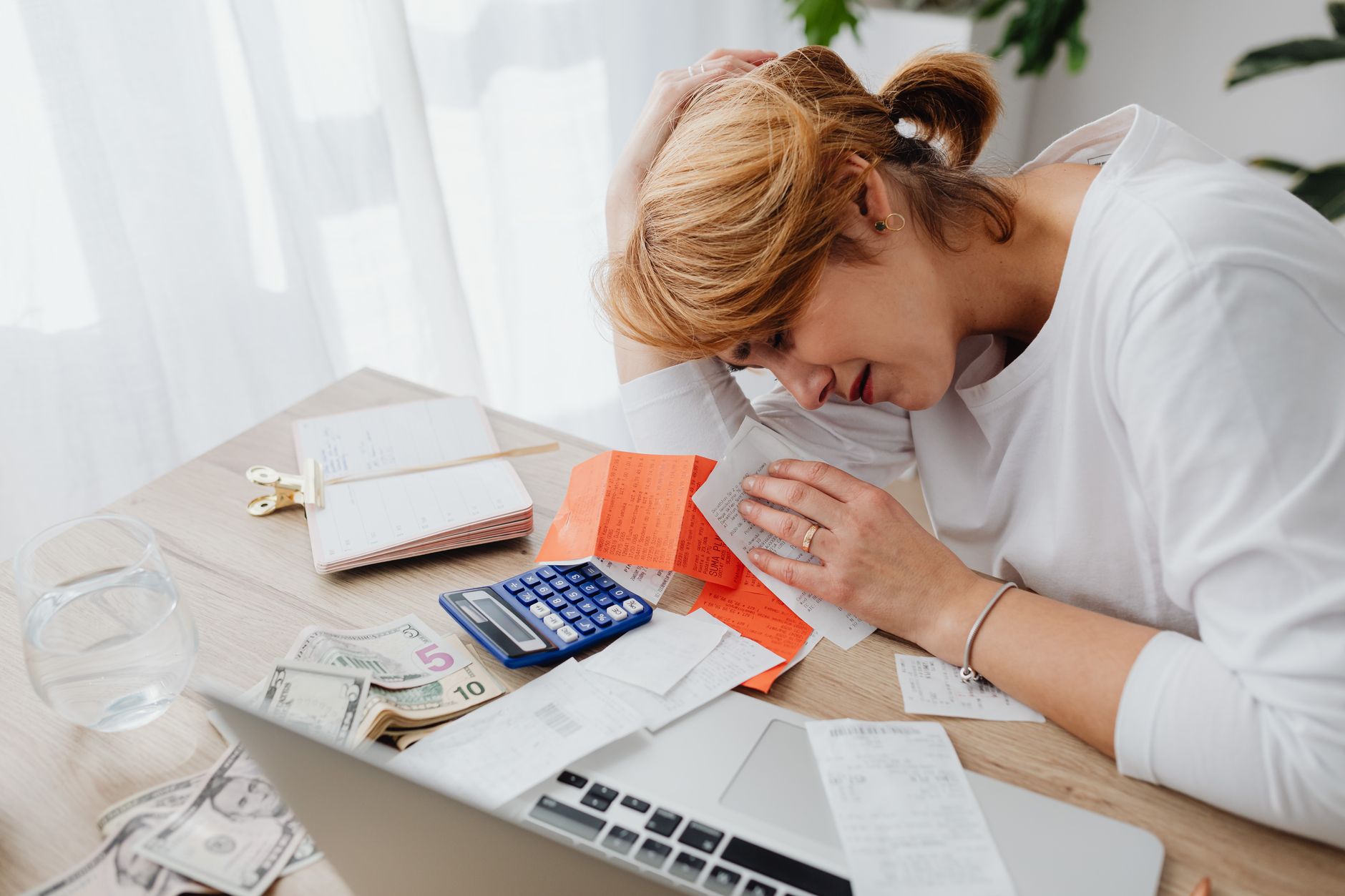 A person sitting at a desk looking slightly overwhelmed but determined while reviewing bills