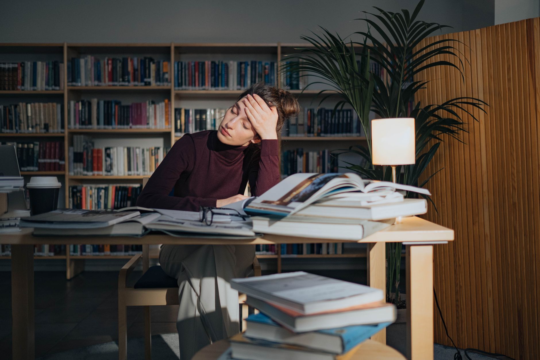 A person sitting at a desk looking at a computer screen with a determined expression, holding a phone to resolve a credit dispute