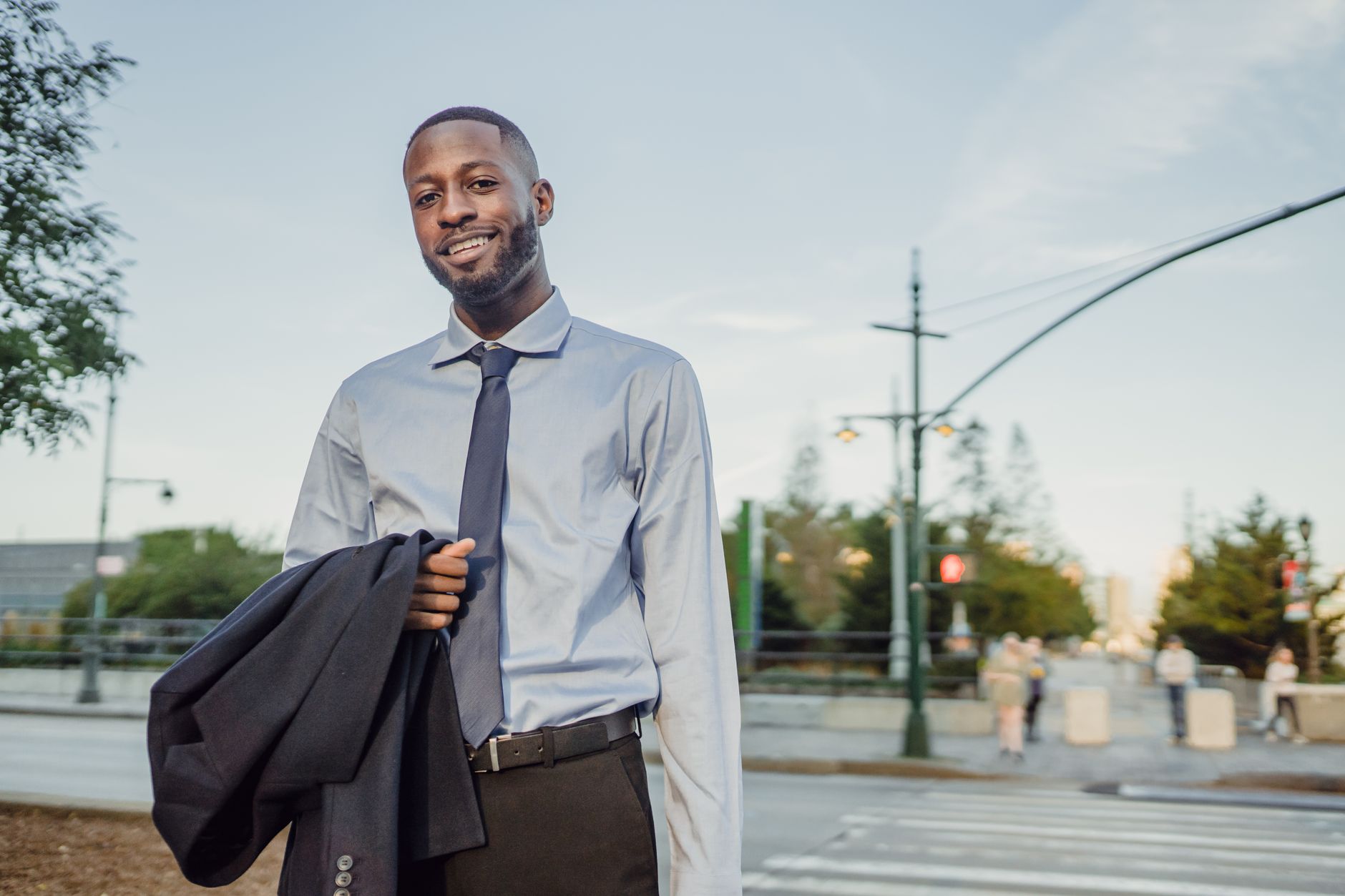 A young professional smiling in an office environment holding a digital tablet to manage finances