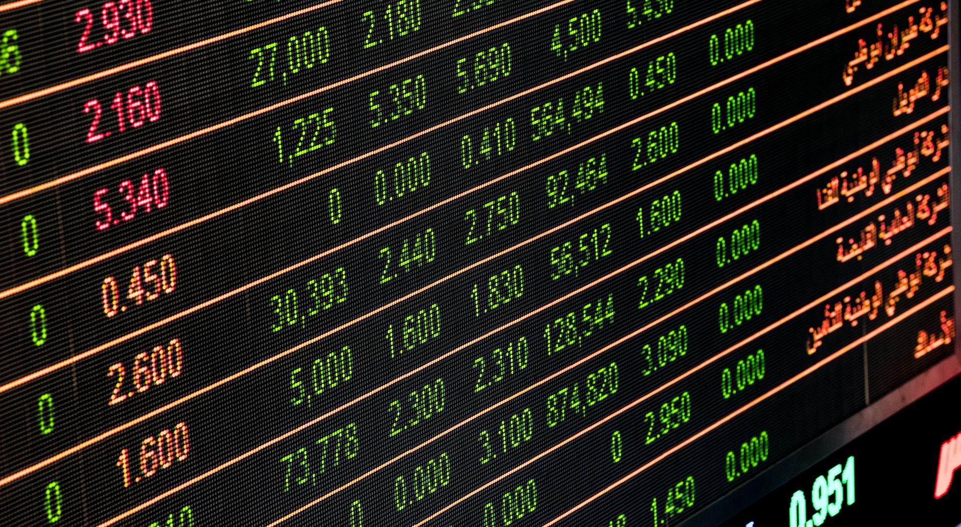 A person reviewing stock market data on multiple screens, with charts and numbers related to index funds and ETFs.