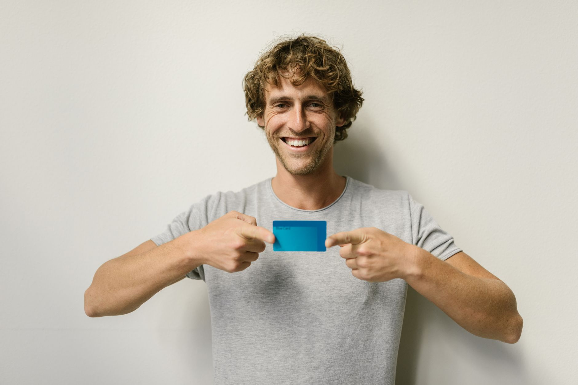 A young adult holding their first credit card while smiling at a laptop screen, symbolizing the start of their credit journey.
