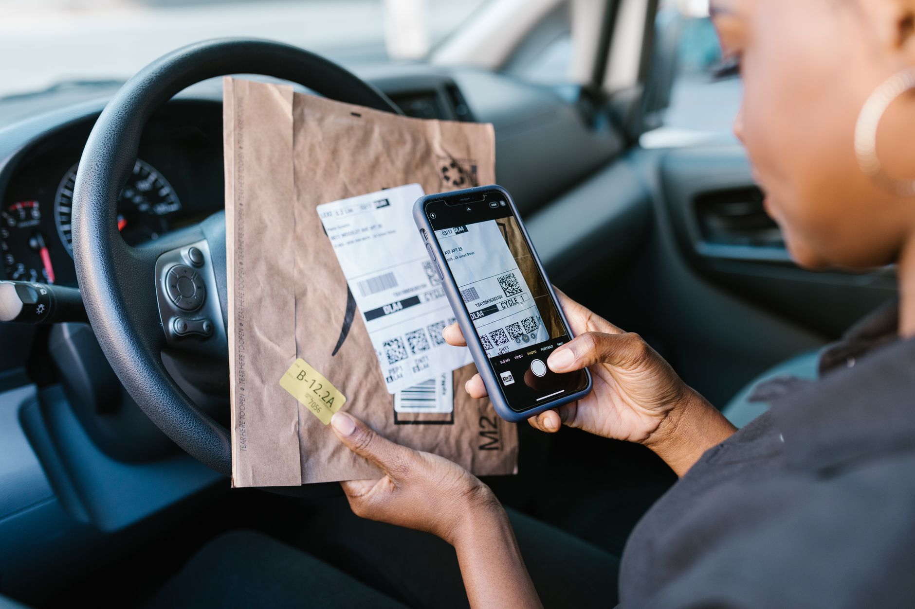 A delivery driver checking a smartphone navigation app while sitting in a car