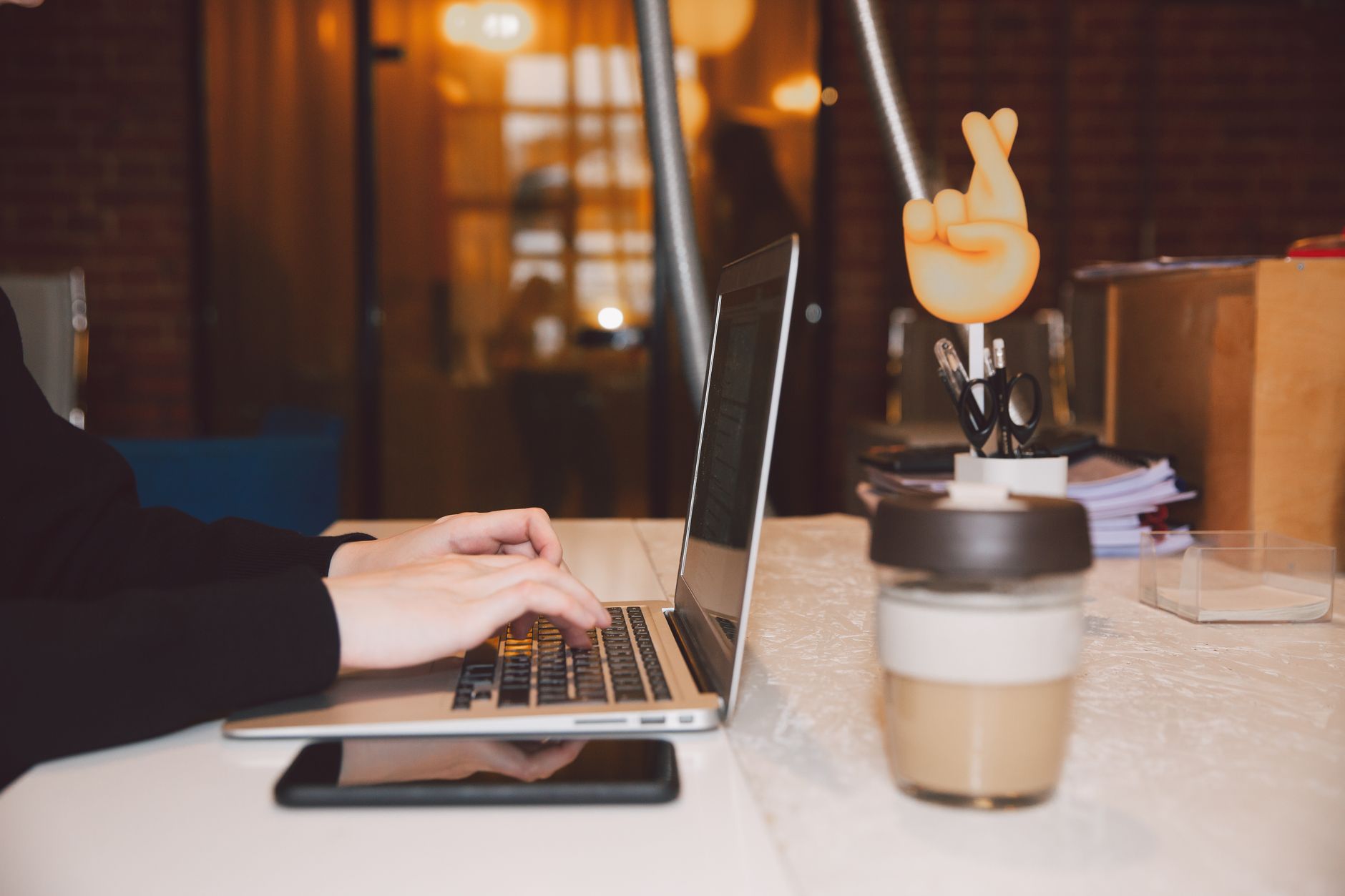 A remote virtual assistant typing on a laptop with organized planners on the desk