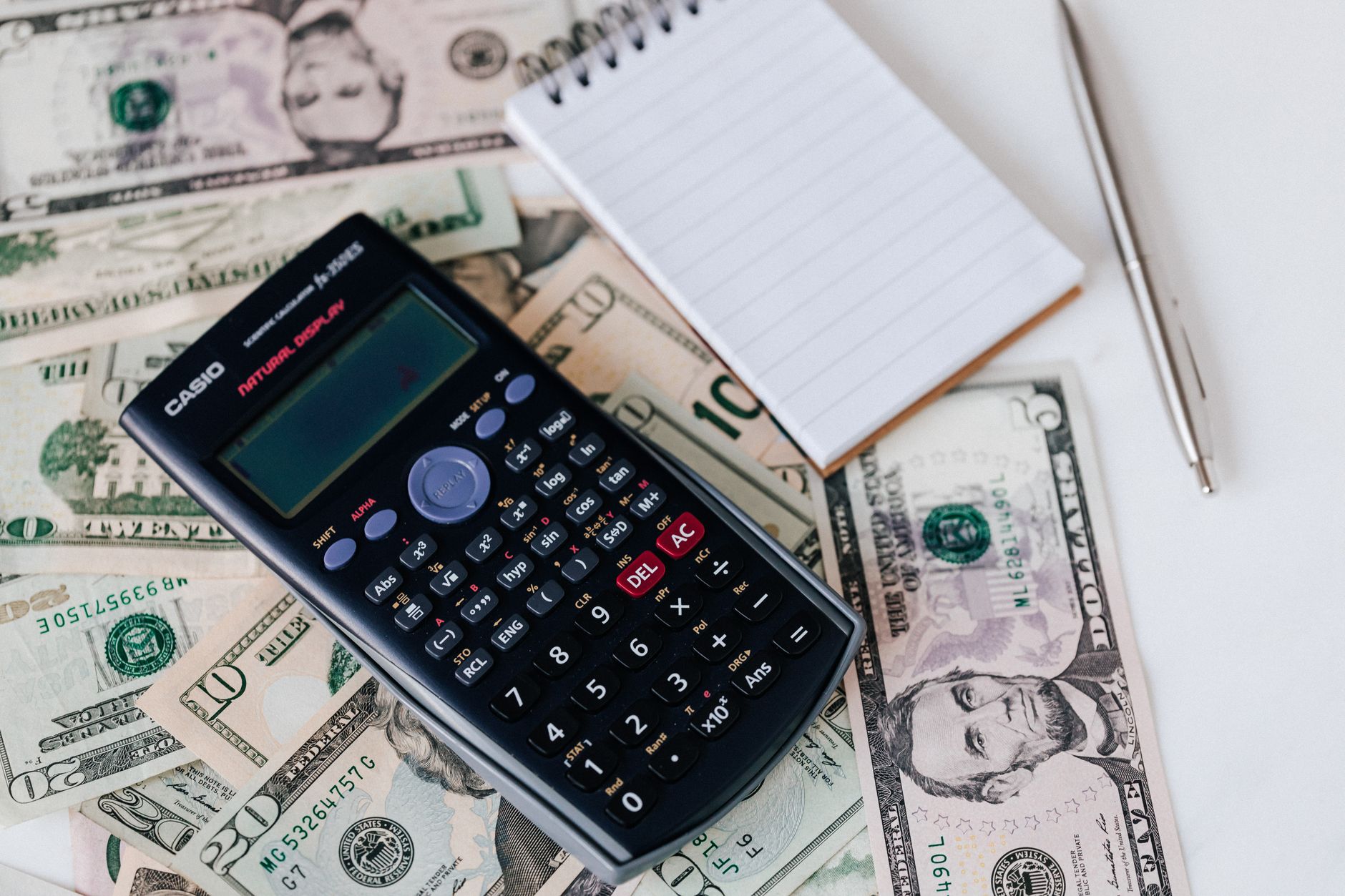 A calculator next to a notepad displaying financial calculations for a home purchase
