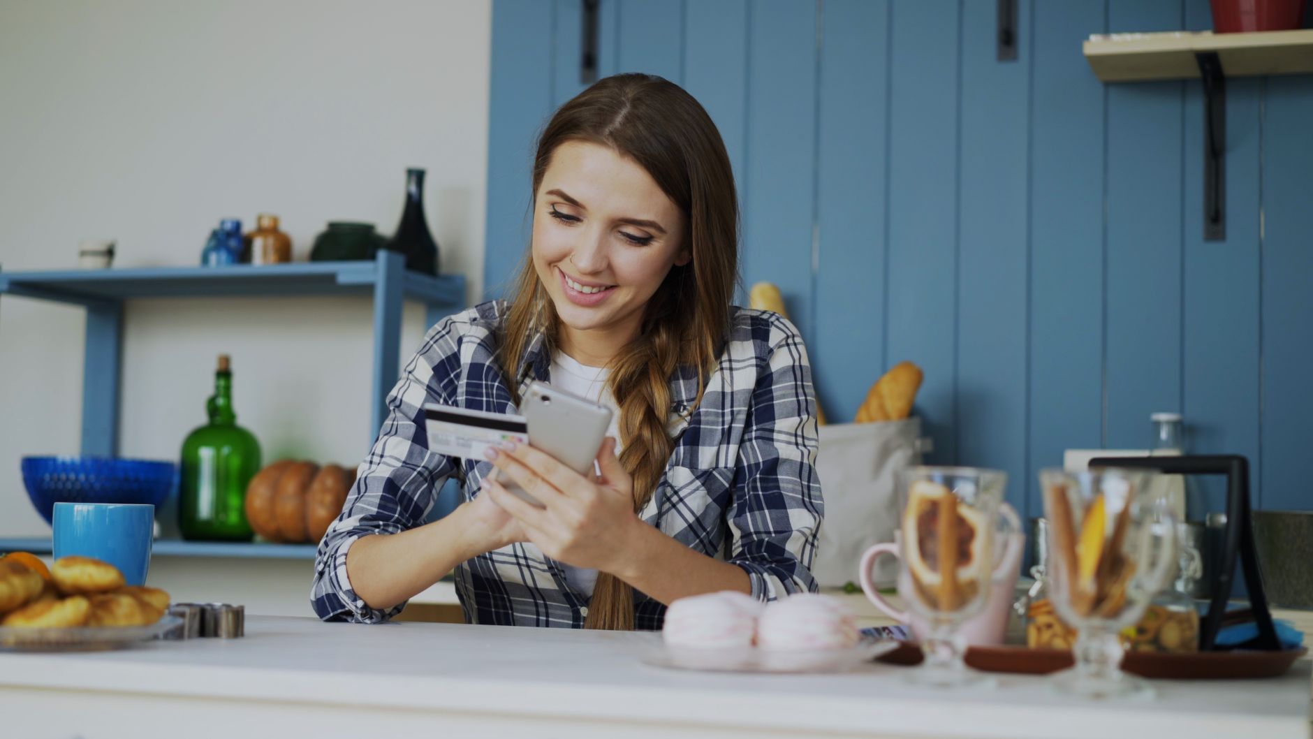 A young adult smiles at a laptop showing a rising credit score graph after being added as an authorized user