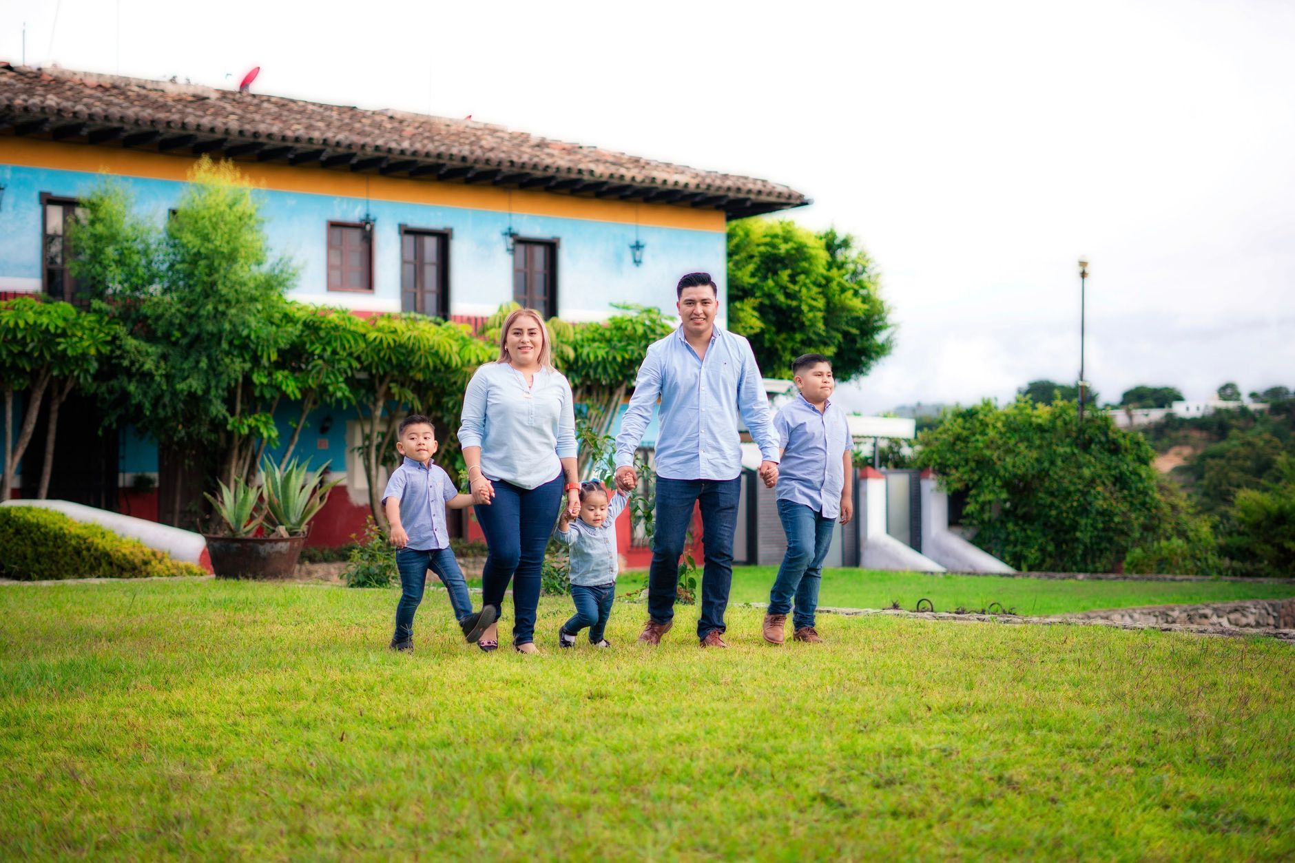 A family standing in front of their suburban home reviewing insurance documents on a tablet