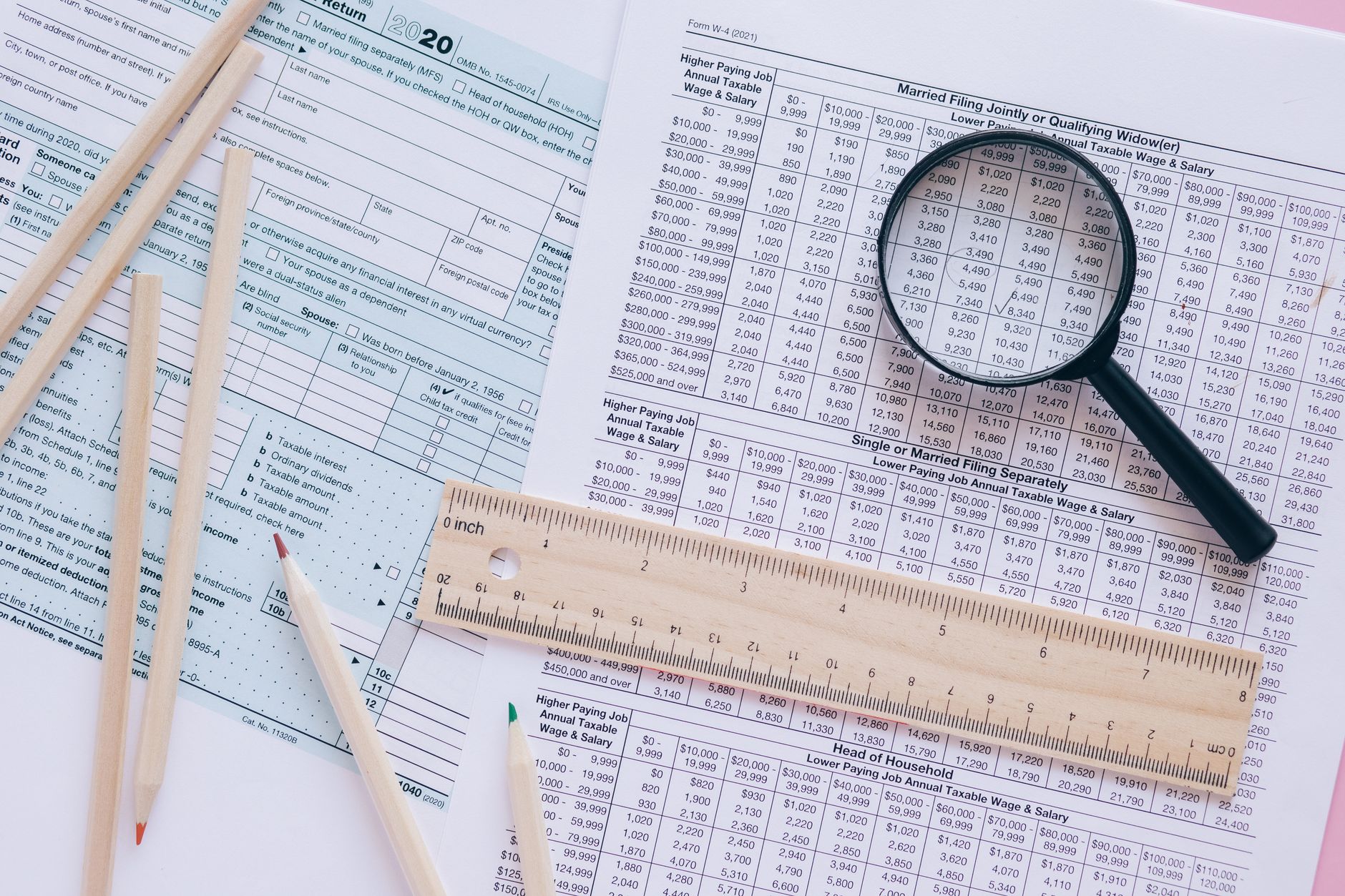 A wooden balance scale with tax forms on one side and dollar coins on the other, representing how federal tax brackets are balanced.