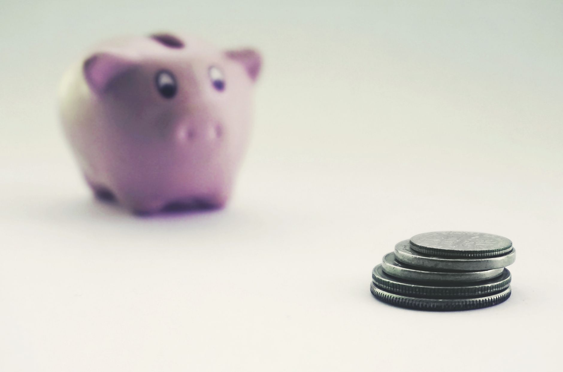 A classic ceramic piggy bank surrounded by neatly stacked coins and a laptop, illustrating tax savings strategies.