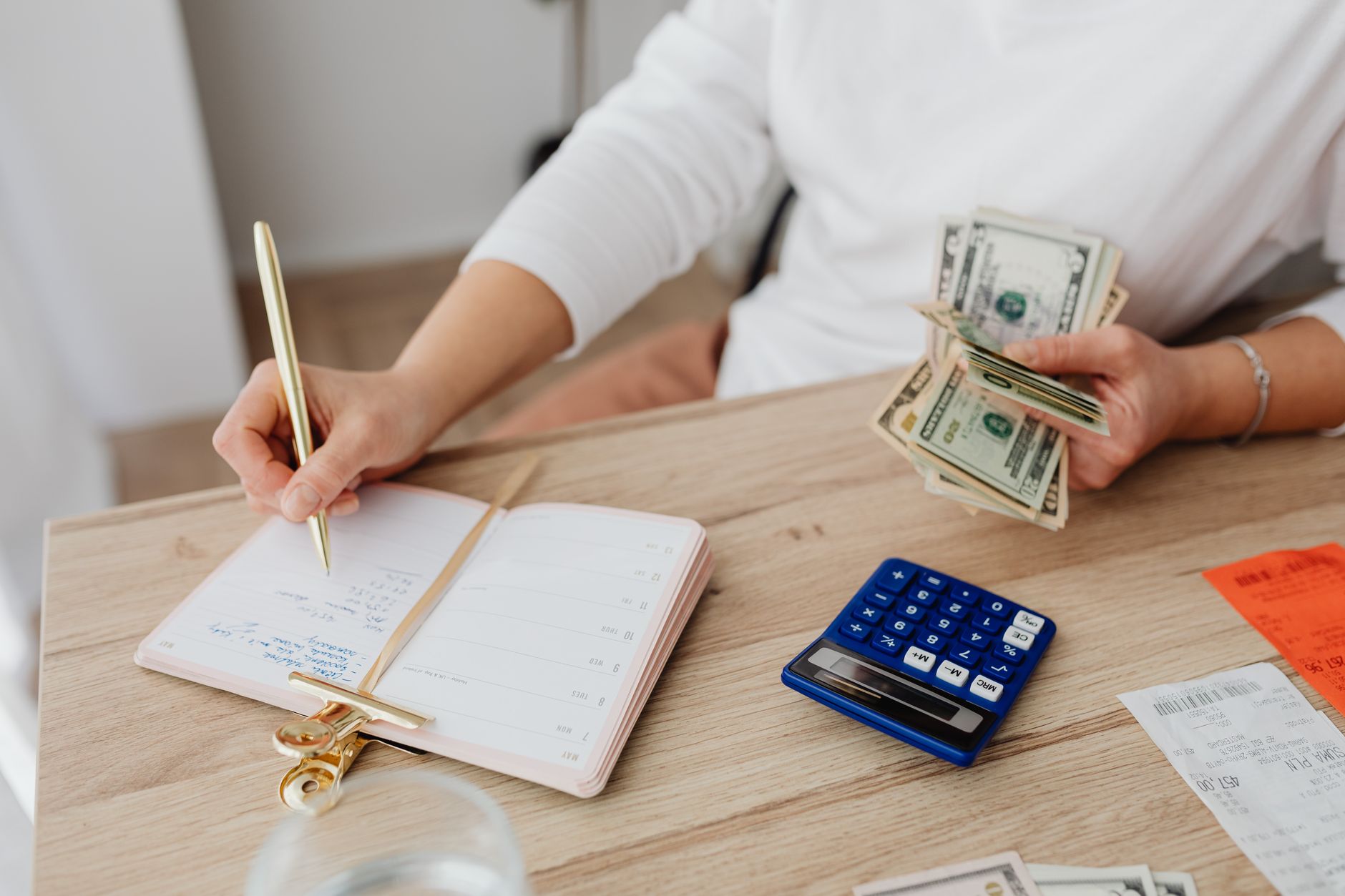 An individual tracking their monthly expenses on a spreadsheet to stop living paycheck to paycheck
