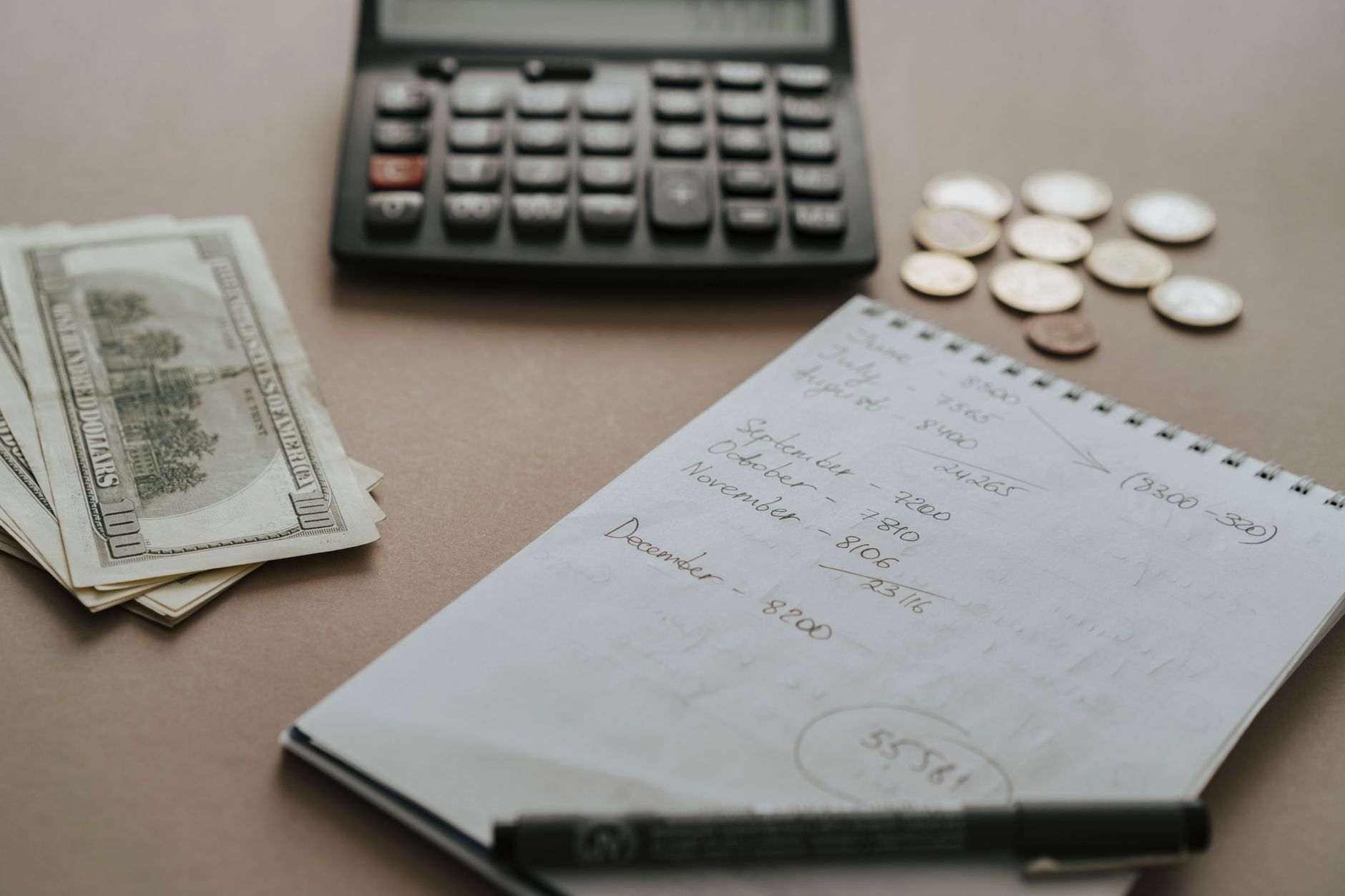 A young teen girl using a notebook and calculator to track her savings goals at her desk