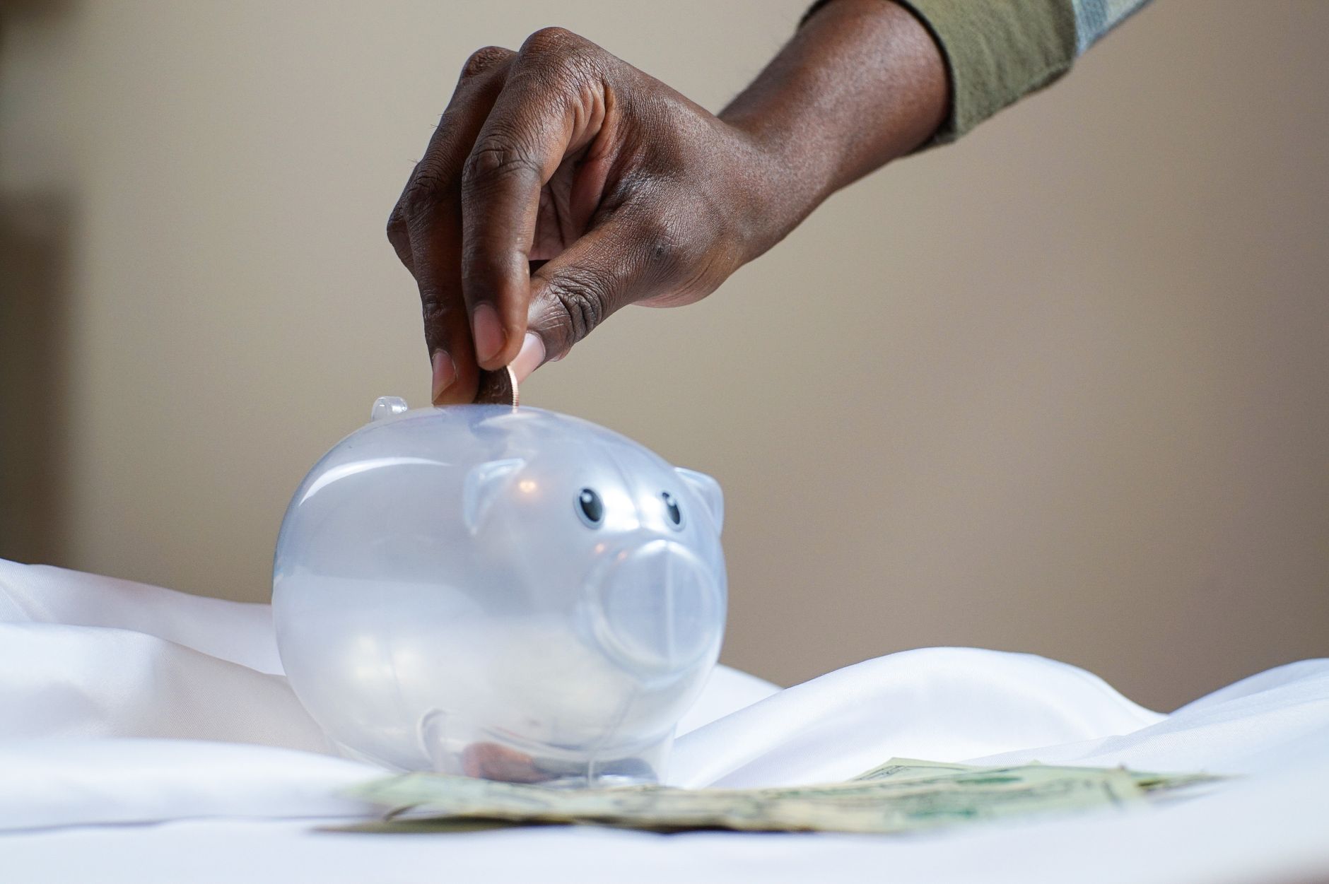 A clear glass jar labeled sinking funds filled with dollar bills and coins on a wooden table