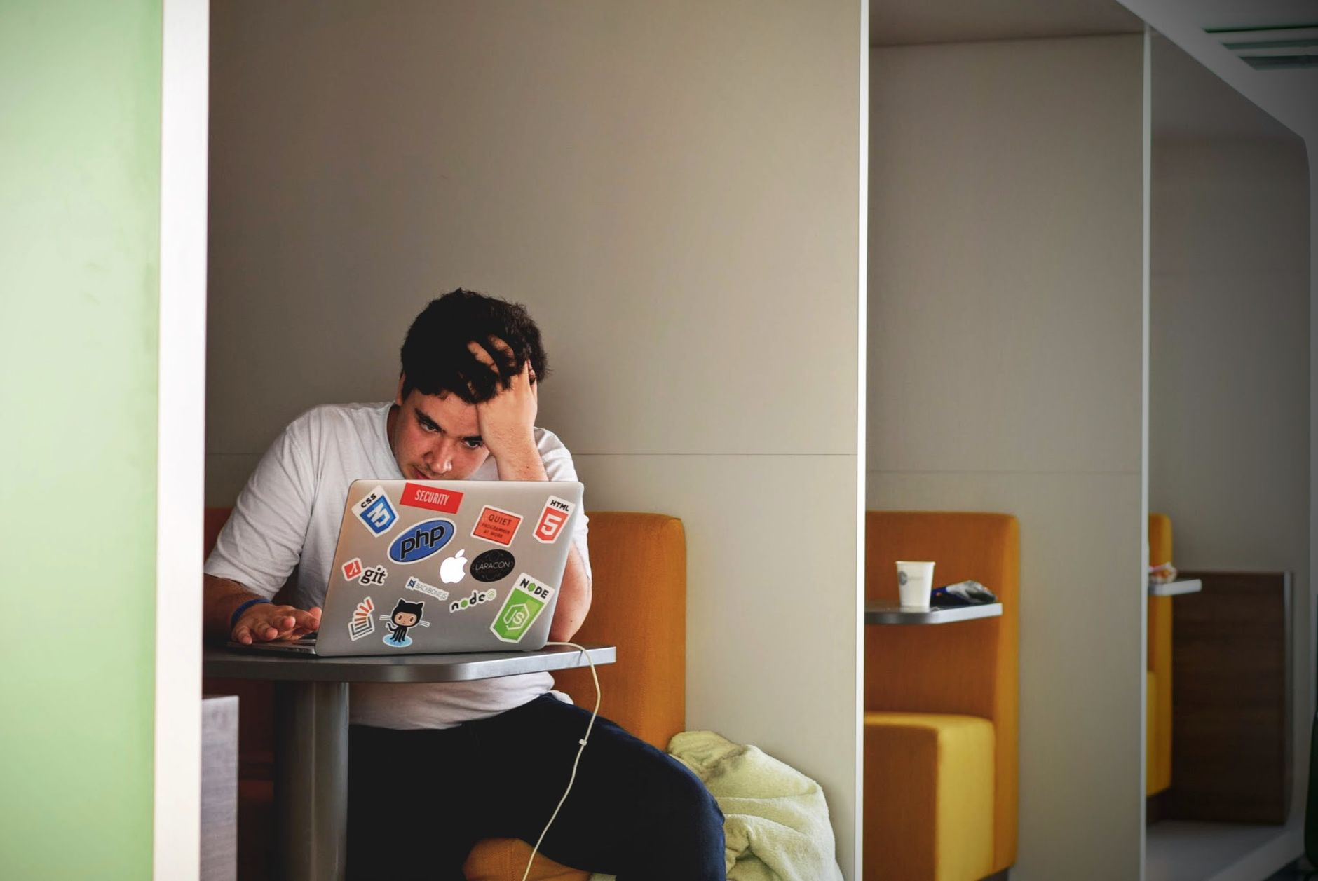A person sitting at a desk with their head in their hands looking at a computer screen.