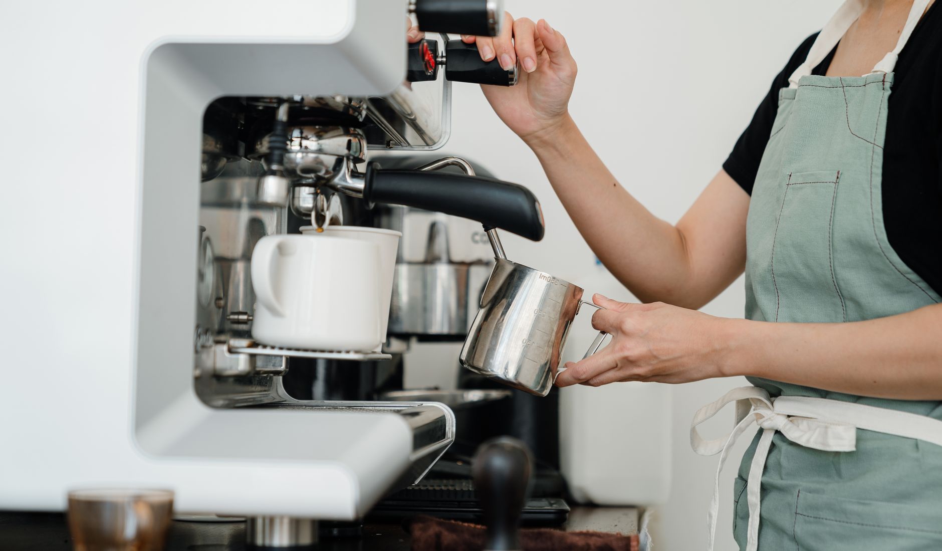 A smiling barista preparing a cup of coffee in a bright modern cafe, representing Barista FIRE.