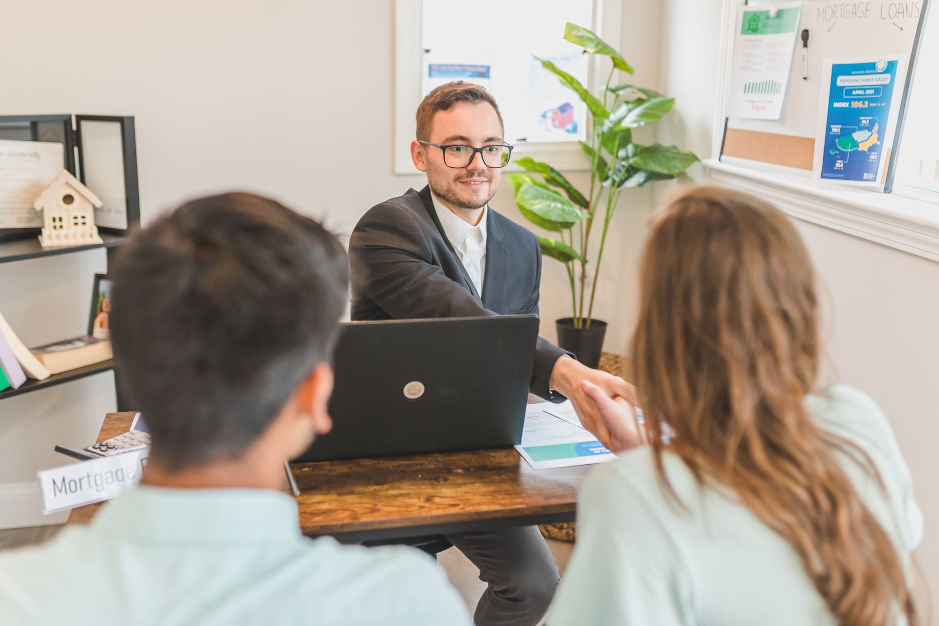 A first-time homebuyer couple sitting with a mortgage loan officer reviewing loan term options and monthly payment scenarios