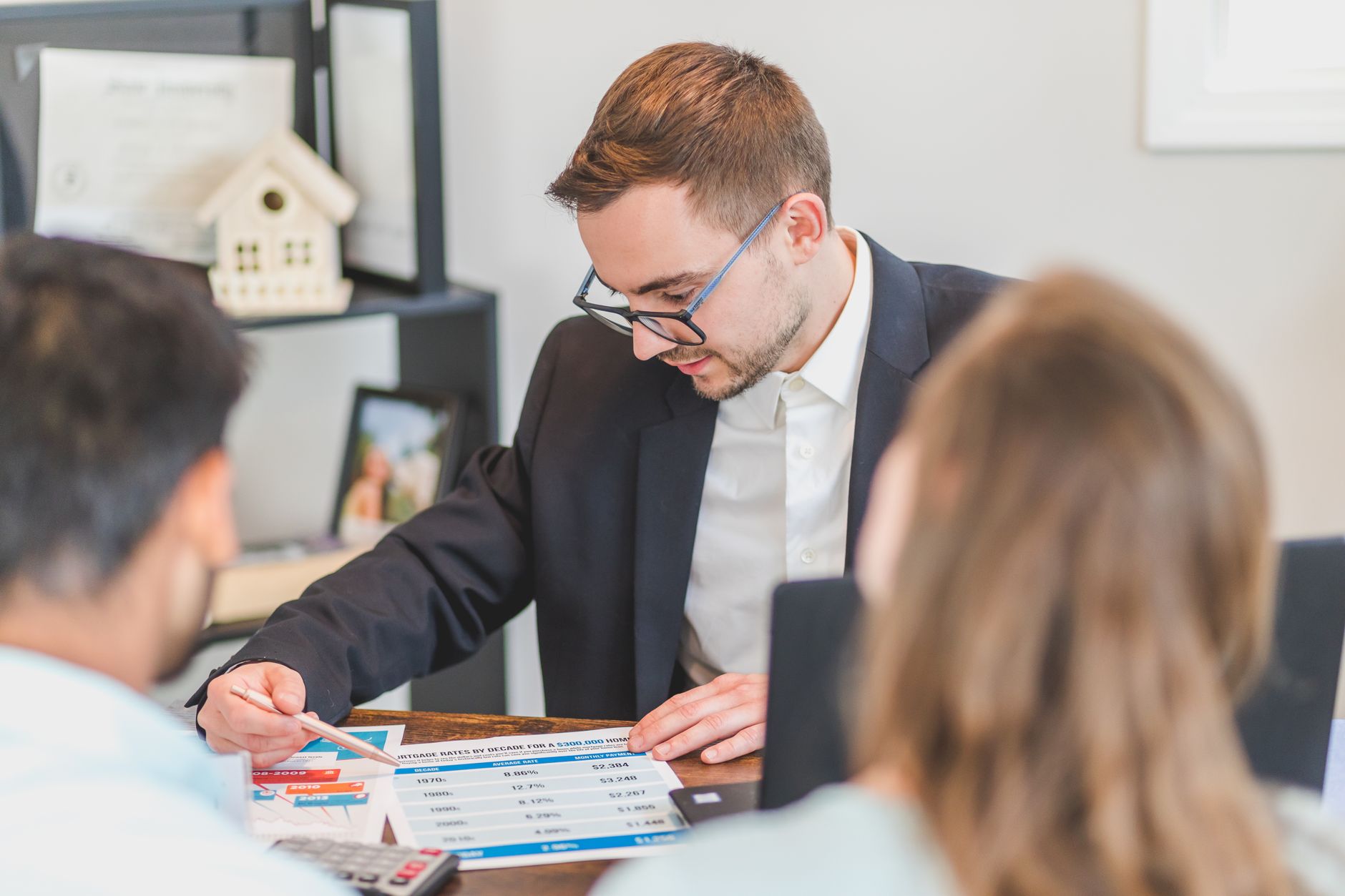 A homeowner reviews mortgage documents and a calculator at a kitchen table, illustrating the cost of private mortgage insurance