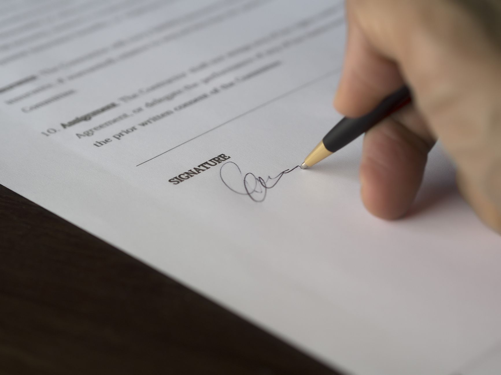 A close-up of two people signing loan documents at a table, highlighting the cosigner's signature line