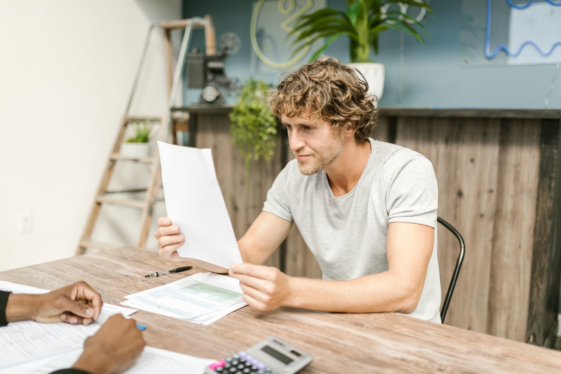 A person sitting at a desk reviewing loan paperwork with a concerned expression, representing the process of seeking cosigner release