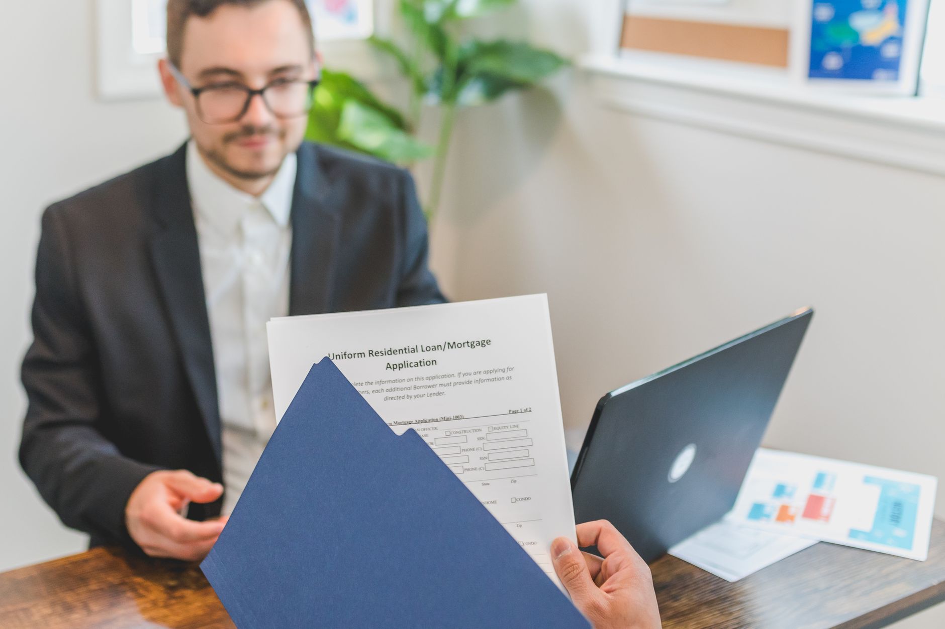 A borrower signs loan documents at a closing table with escrow waiver forms visible